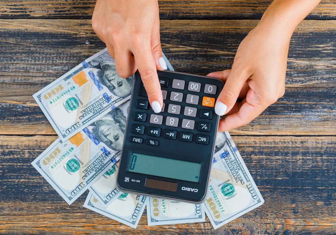 Mujer contando dinero usando una calculadora